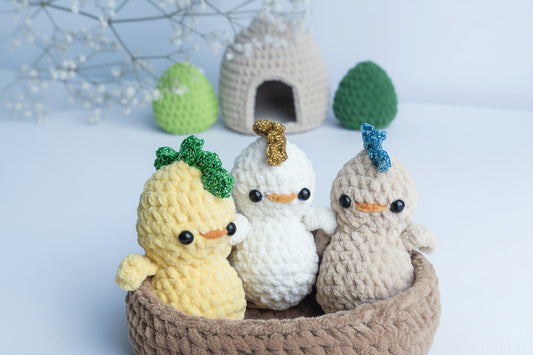 Three crochet baby chicks sitting together in a handmade crochet nest, soft yarn amigurumi decoration.