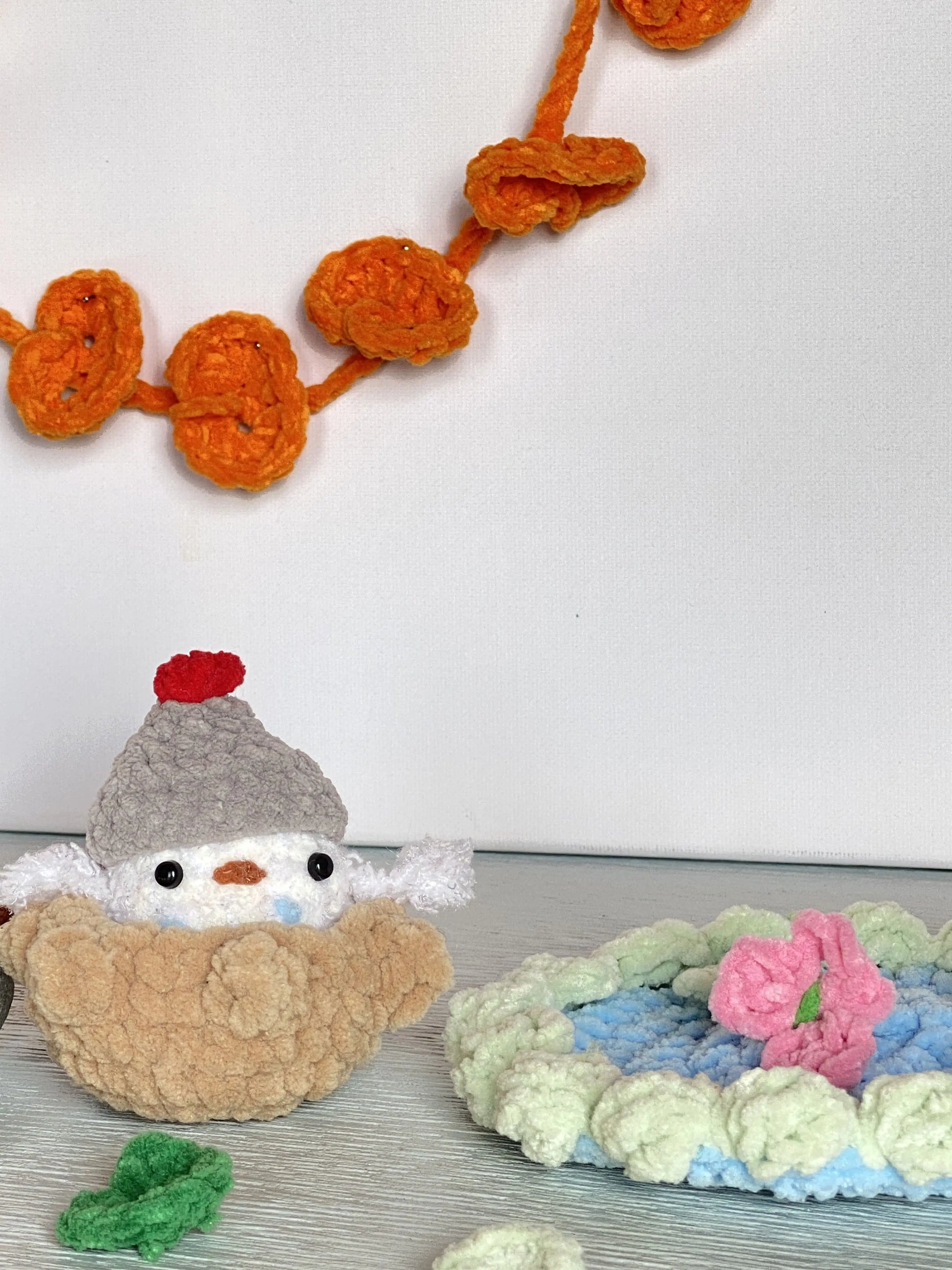 Cute crochet duckling wearing a beanie, in a pond with flowers and lily pad