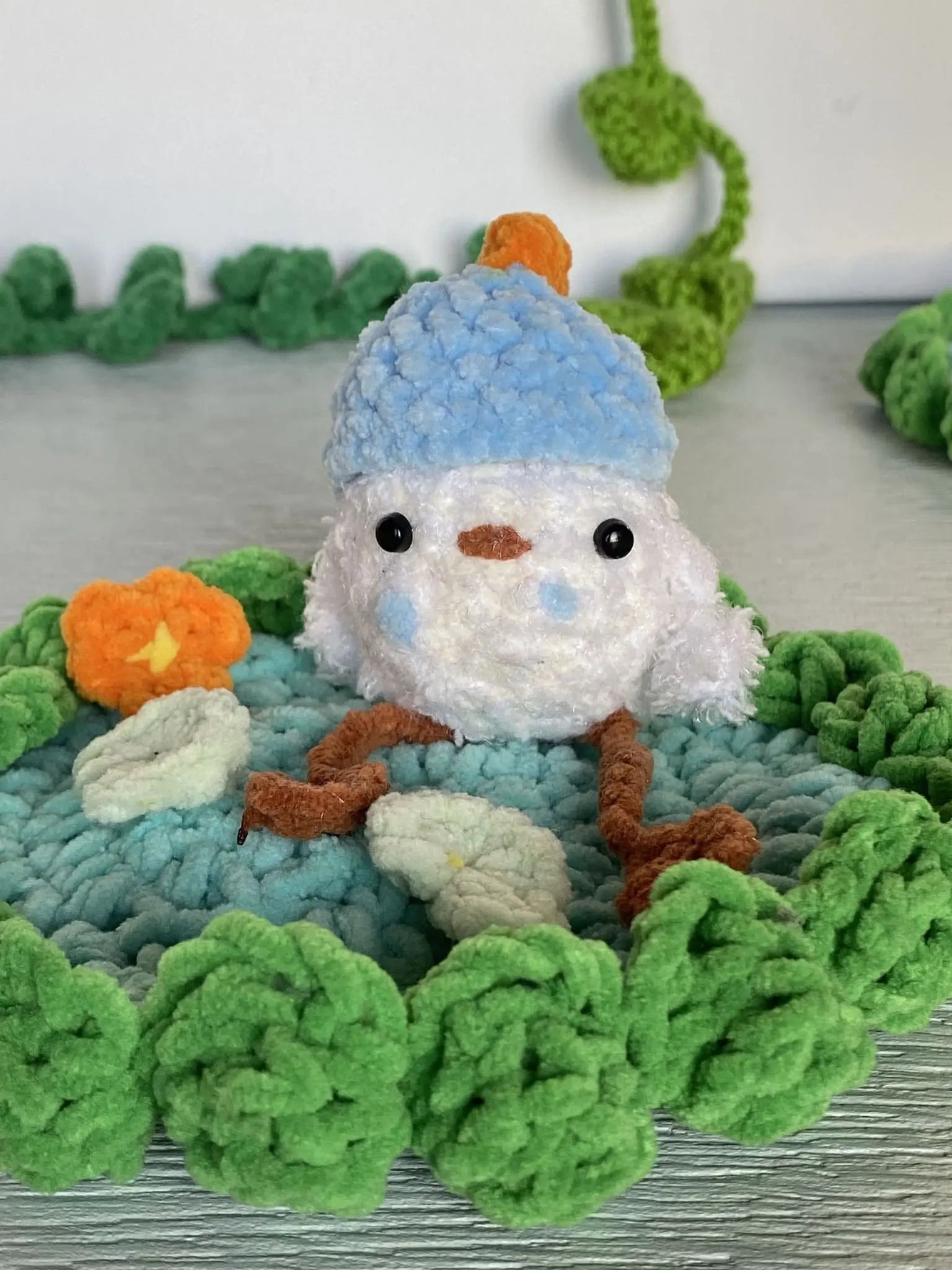 crochet baby duck in pond with a beanie, a flower and a lily pad