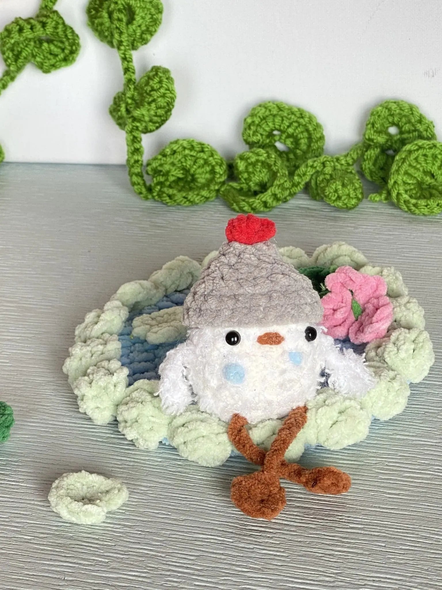 crochet baby duck in pond with a beanie, a flower and a lily pad