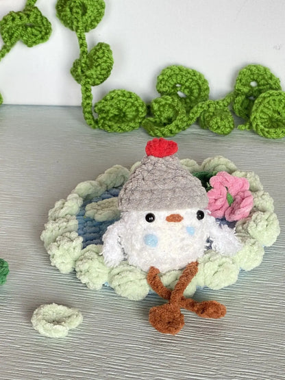 crochet baby duck in pond with a beanie, a flower and a lily pad