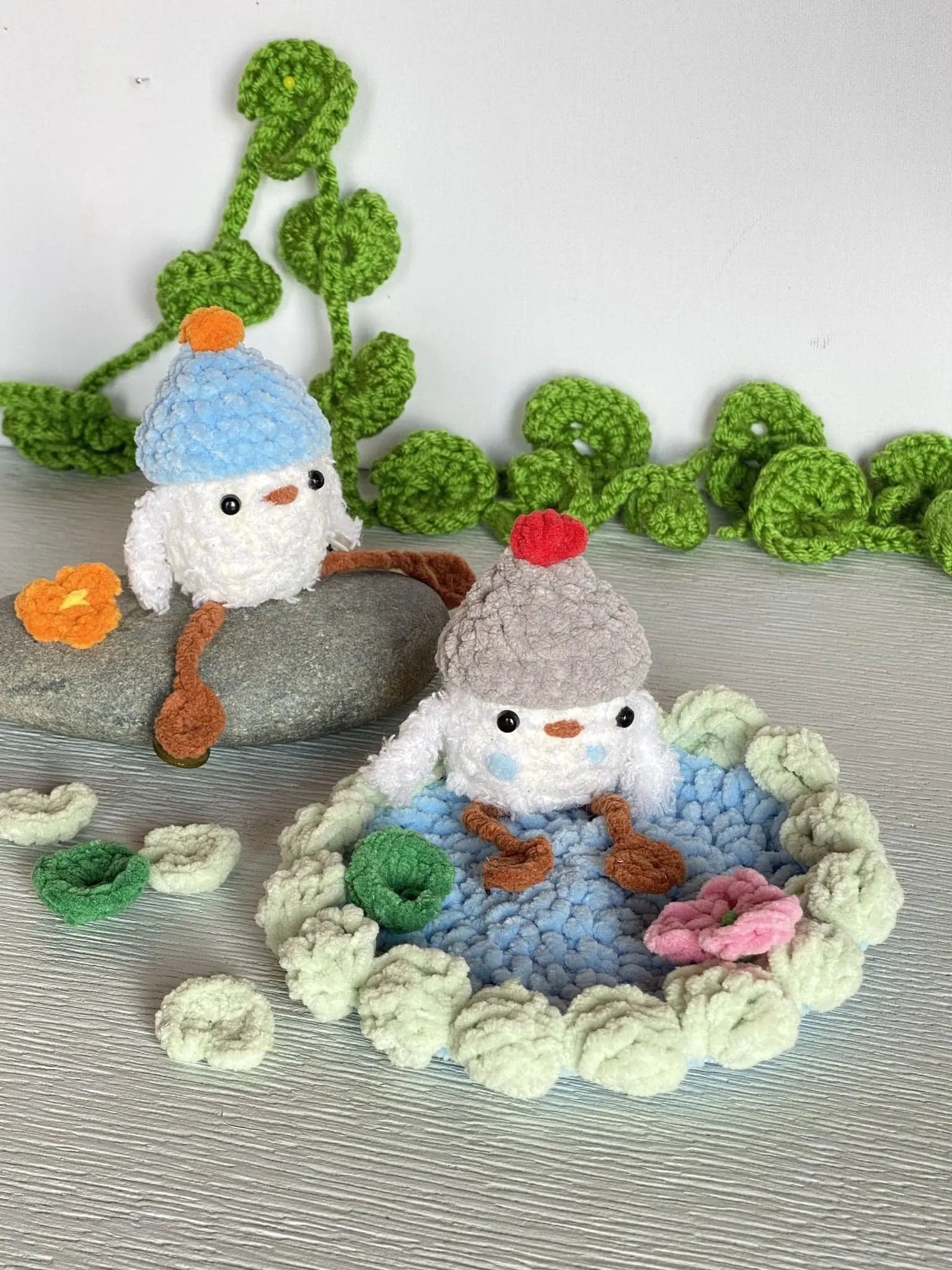crochet baby duck in pond with a beanie, a flower and a lily pad
