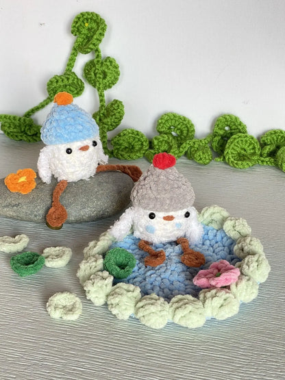 crochet baby duck in pond with a beanie, a flower and a lily pad