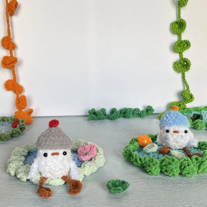 crochet baby duck in pond with a beanie, a flower and a lily pad