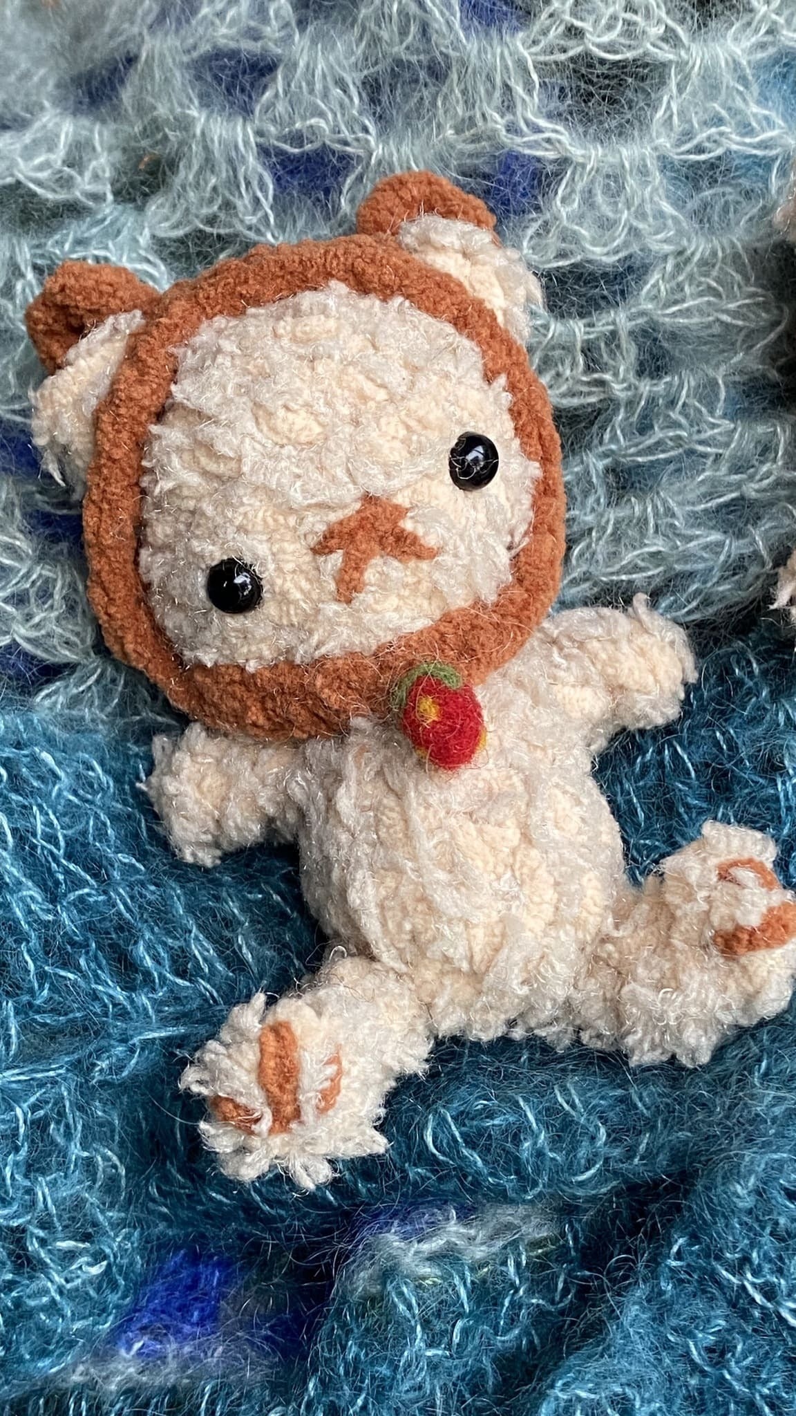 Melennig crochet bear with strawberry necklace sitting on blue mohair blanket  – TchipTchip Studio